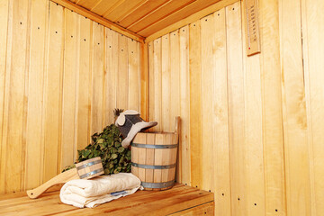 Fototapeta na wymiar Interior details Finnish sauna steam room with traditional sauna accessories basin birch broom scoop felt hat towel. Traditional old Russian bathhouse SPA Concept. Relax country village bath concept