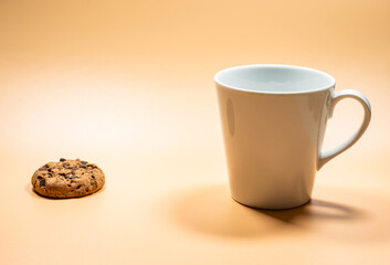 Close up white mug of milk and single dark chocolate chip cookies