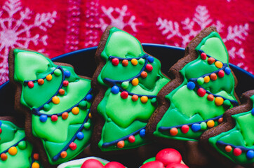 Close-up of beautifully decorated gingerbread Christmas cookies made to look like lit-up Christmas trees on a platter