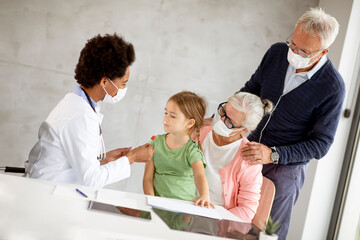 Senior couple with grandaughter at black female doctor