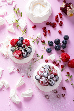 Pavlova meringue cake with cream and berries on dusted sugar pink background
