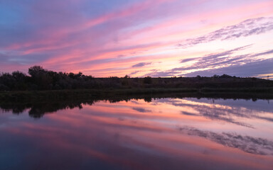 Obraz premium sunset over the river, the sky is reflected in the water, there is a small bridge on the river bank