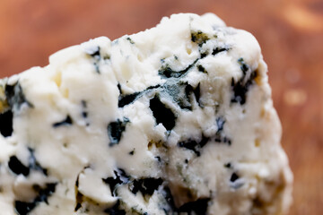 Macro close-up of a French blue cheese roquefort, tangy, crumbly and slightly moist, with distinctive veins of blue mold.