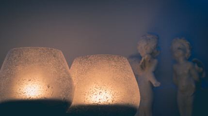 Świeczki w świecznikach,  figurkami aniołków w tle