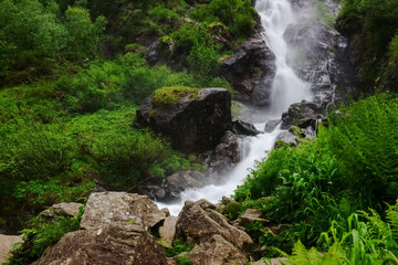 rushing large waterfall with huge rocks while hiking
