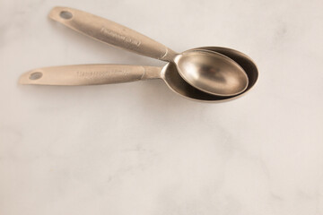 silver measuring spoons sitting on the marble kitchen counter