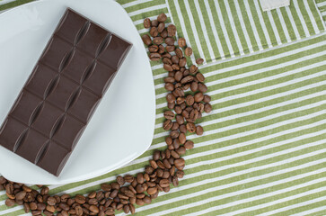 Bar of chocolate with coffee beans on a tablecloth