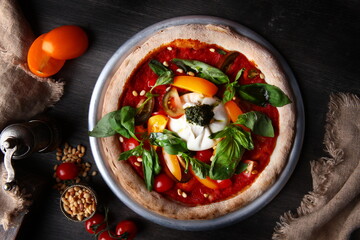 Pizza with burrata cheese and pine nuts. Italian pizza. Metal plate for serving. Green basil...