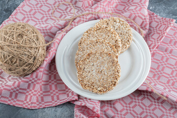 A white plate full of puffed rice bread with a ball of yarn