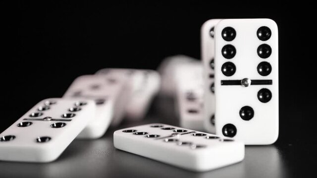 White domino dice fall on a black background. Slow motion