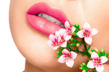 Fototapeta na wymiar Girl lips with pink lipstick. There are pink flowers around the lips..