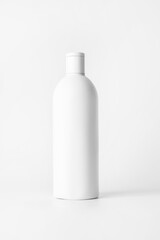 White bottle with shampoo on a light background..