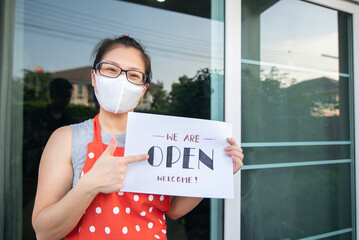 Women Owner holds Open sign at front restaurant 