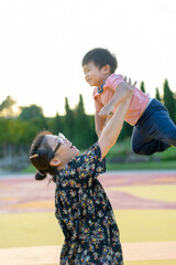 Asian Mother lifted her child into the air at the park
