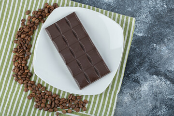Bar of chocolate with coffee beans on a tablecloth