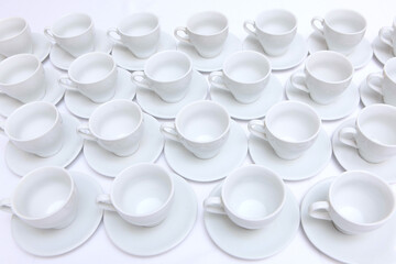 Empty tea-drinking utensils in large quantities. Catering or banquet concept. White porcelain tea cups and saucers. View from above.