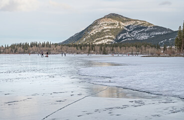 People ice skating and playing hockey on frozen Lac des Arcs in Alberta, Canada
