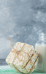 Delicious square crispbread and bottle of milk on marble background