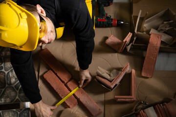 The construction worker looks at the camera and smiles while measuring. Wearing personal protective...