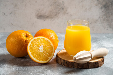 Glass cups of orange juice and a wooden reamer