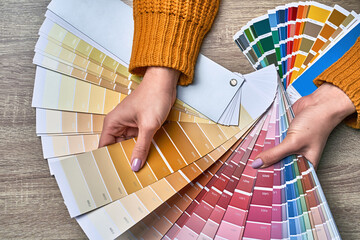 Color wheel for choosing paint tone. Hands of female interior designer working with palette for...