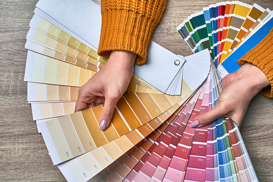 Color wheel for choosing paint tone. Hands of female interior designer working with palette for choosing colors. Creative process concept. Comparing options with matching hues.
