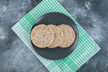A black plate full of crispy rice bread on a tablecloth