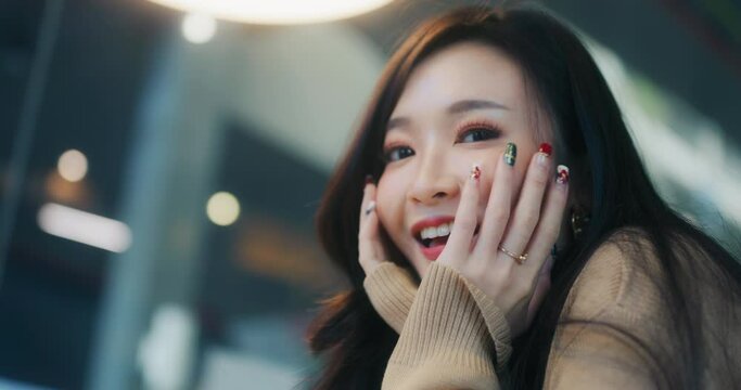 Beautiful young Asian woman smile happily, wave and look at camera. Handheld slow motion. People casual leisure, happiness, cafe lifestyle, or cosmetic skincare concept. Shot on RED Komodo 6K