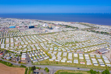 Aerial photo of the Fantasy Island caravan camping resort park in the village of Skegness showing rows of caravans and the amusement park by the ocean and sandy beaches