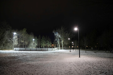 Deserted outdoor hockey rink in urban park at night closed due to COVID-19