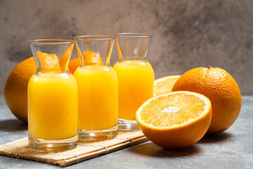 Obraz na płótnie Canvas Glass jars of orange juice and sliced orange