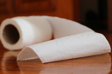 Slightly unrolled toilet paper roll on the wood floor. Toilet paper roll falling to the floor