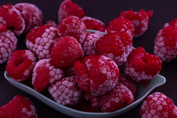 Frozen Raspberries in a Bowl placed on a black background