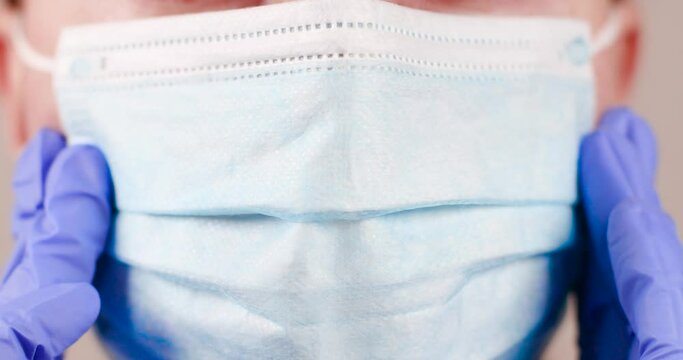 Close up shot of female face mouth wears protective medical mask and blue surgical rubber gloves in clinic laboratory during covid-19 coronavirus pandemic