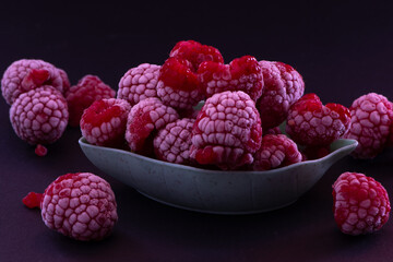Frozen Raspberries in a Bowl placed on a black background