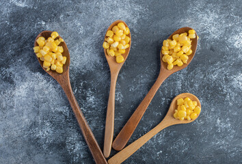 Wooden spoons of sweet corns on marble background