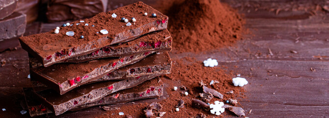 Organic food snack tasty sweet dessert milk dark chocolate bar macro closeup broken slide piece and fruit orange raspberry hazelnut nuts on cocoa cacao powder wooden table for new year Christmas gift