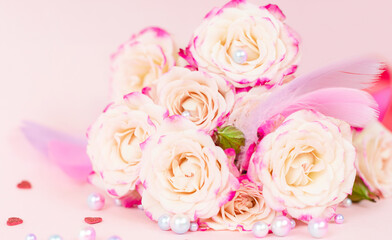 delicate bouquet of bushy peony roses with bright ribbons, pearls, feathers and hearts  on a pink background, the concept of congratulations on Valentine's day