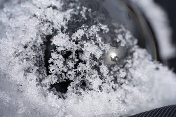 Glass ball in snow covered with ice and snow flakes