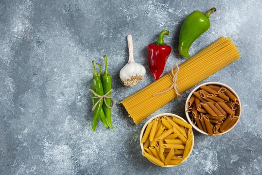 Raw spaghetti with vegetables on a wooden board