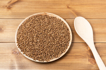 Buckwheat groats on the plate on natural wood table background.