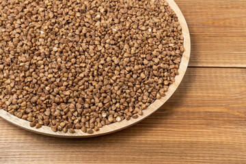 Plate of buckwheat groats on the wooden table, close up.
