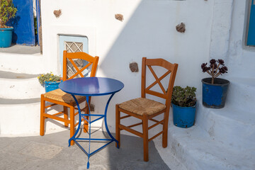 Fototapeta na wymiar Table and chairs on street in Pyrgos, the most picturesque village of Santorini. Cyclades Islands, Greece