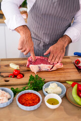 The chef examines the meat softness on a wooden kitchen board