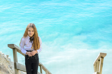 Portrait of a beautiful girl ten years old, in the background a blue-white sea