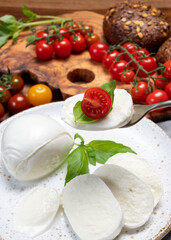 Cheese collection, eating. of white soft Italian cheese mozzarella, served with red cherry tomatoes, fresh basil leaves