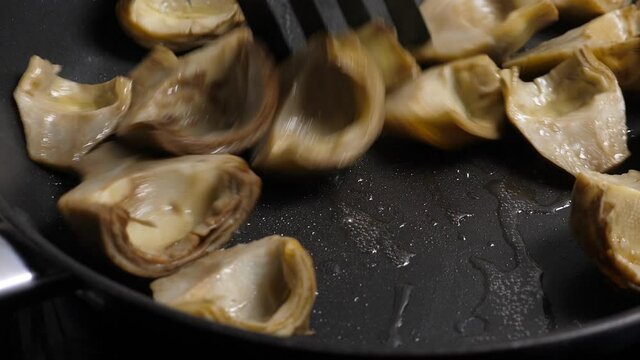 Cooking artichoks on frying pan. Closeup