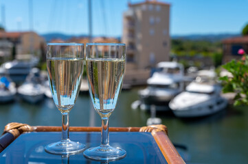 Summer party with sparkling champagne wine and sail boats haven of Port Grimaud on background, Provence, France