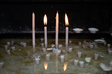 Two burning candles in the Christian church with flame reflection on the surface of water.