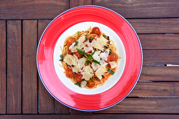 Spaghetti pasta with cherry tomatoes, parmesan cheese and herbs. Healthy vegan food concept, top view